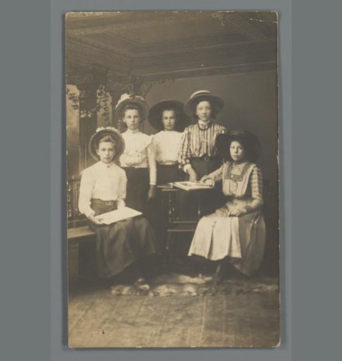 Group portrait of five unknown girls in a photography studio with a photo album