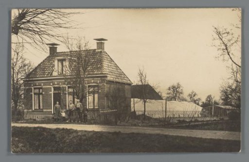 Peasant family in front of a house with greenhouses behind