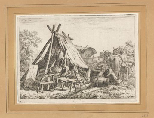Soldier cutting wood by a tent